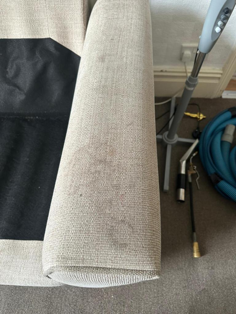 arm of a light coloured fabric sofa showing marks and dirt before cleaning