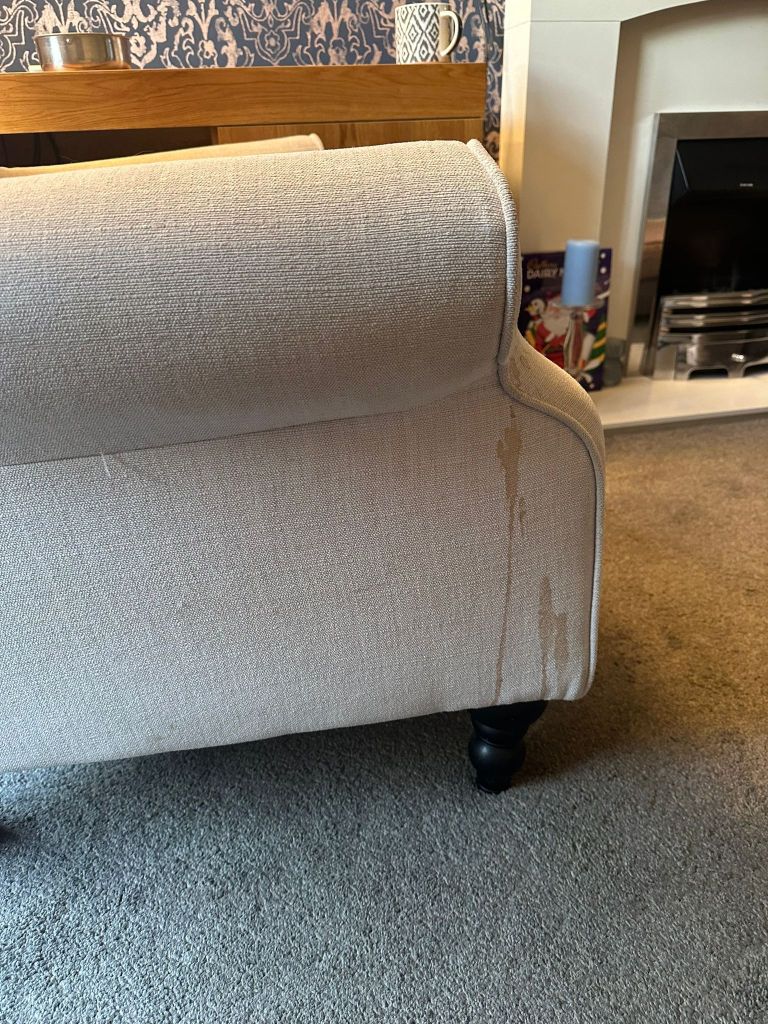 side of a light coloured fabric sofa showing tea stain before cleaning